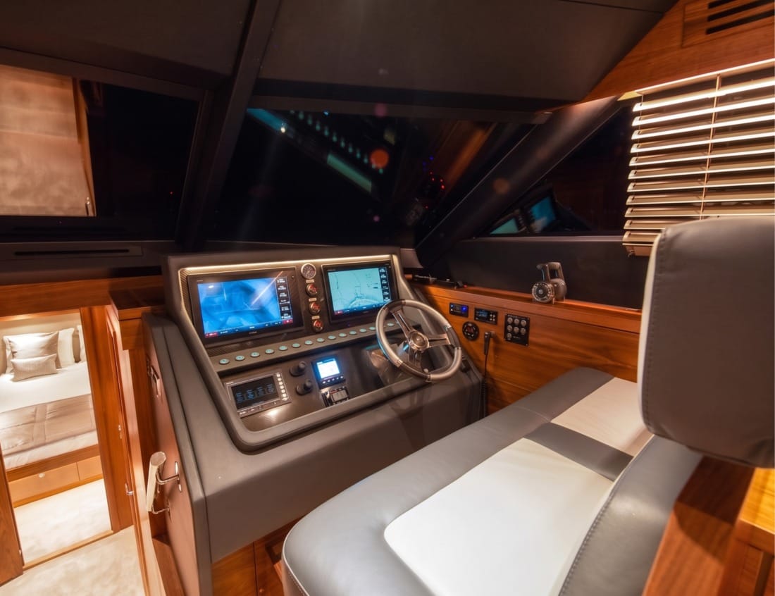 Helm station of a Phantom 65 Coupé yacht with steering wheel and navigation screens.