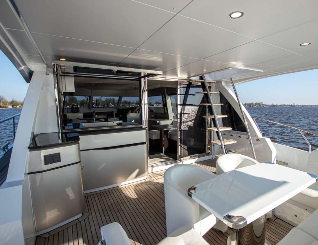Aft deck dining area of a Phantom 70 yacht with stairs to the flybridge