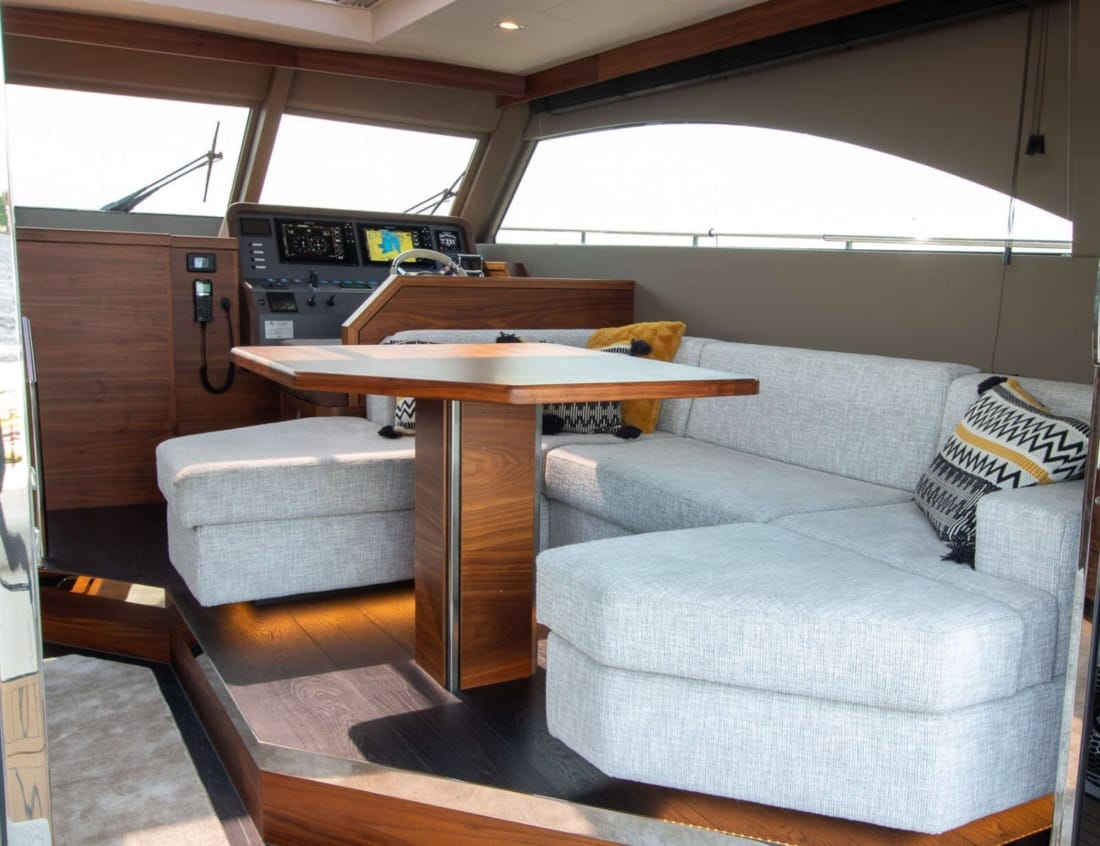 Interior of an Exclusive Deluxe 1700 - Exclusive Series with seating area, table and helm station.