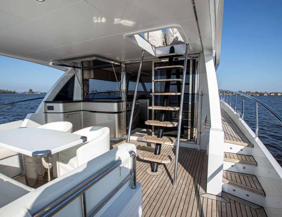 Aft deck dining area of a Phantom 70 yacht with stairs to the flybridge