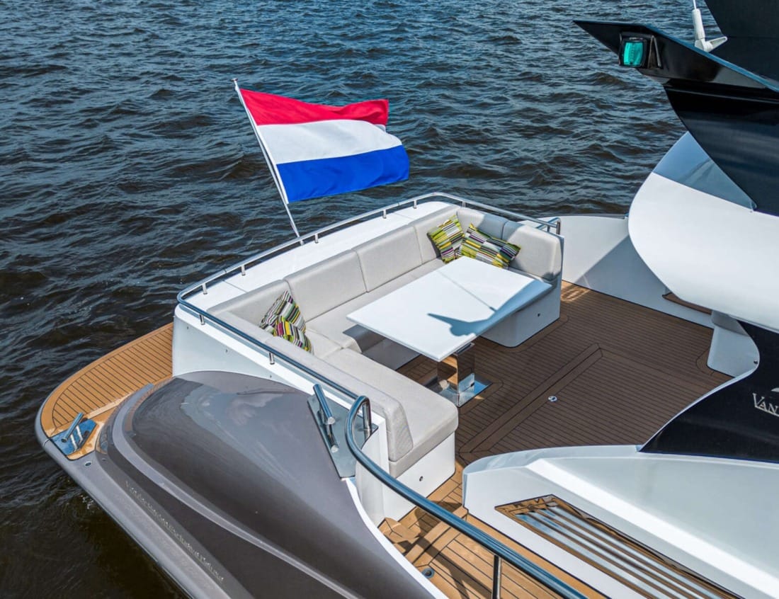 Aft deck seating area of an Exclusive Deluxe 1700 - Exclusive Series with table and Dutch flag.
