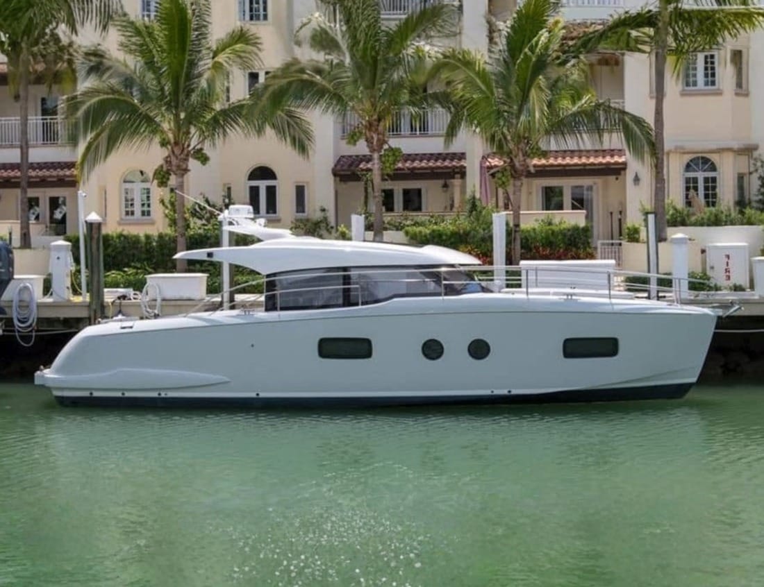 Side view of a Hayden Sedan - Hayden Series moored in a waterfront marina with palm trees.