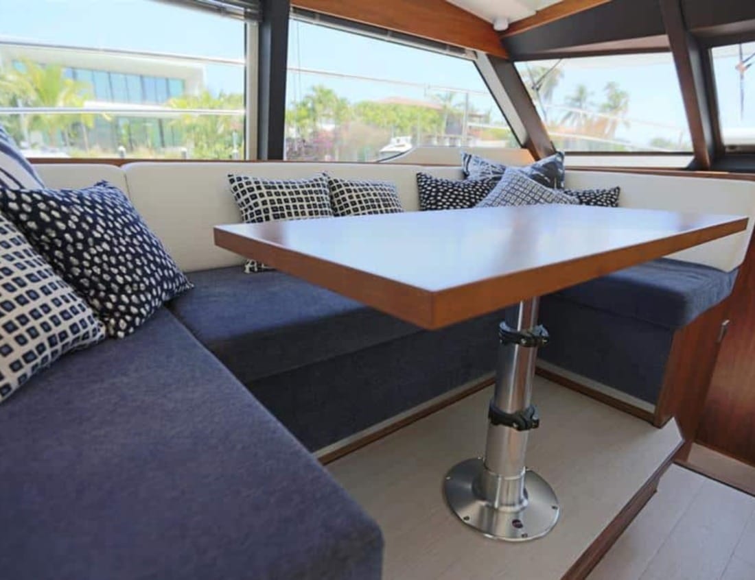 Interior dining area of a Hayden Sedan - Hayden Series with blue seating, wooden table and panoramic windows.