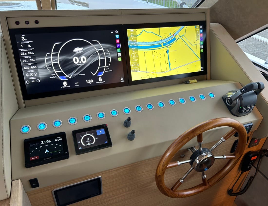 Helm station of a Traveller 63 - Traveller Series with navigation displays, wooden steering wheel and throttle controls.
