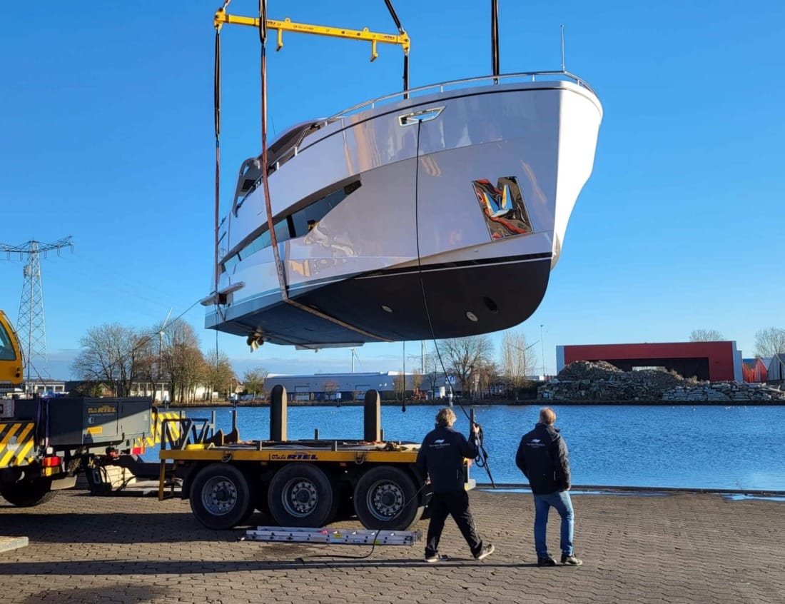 Traveller 63 - Traveller Series being lifted by a crane above a transport trailer at the waterfront.