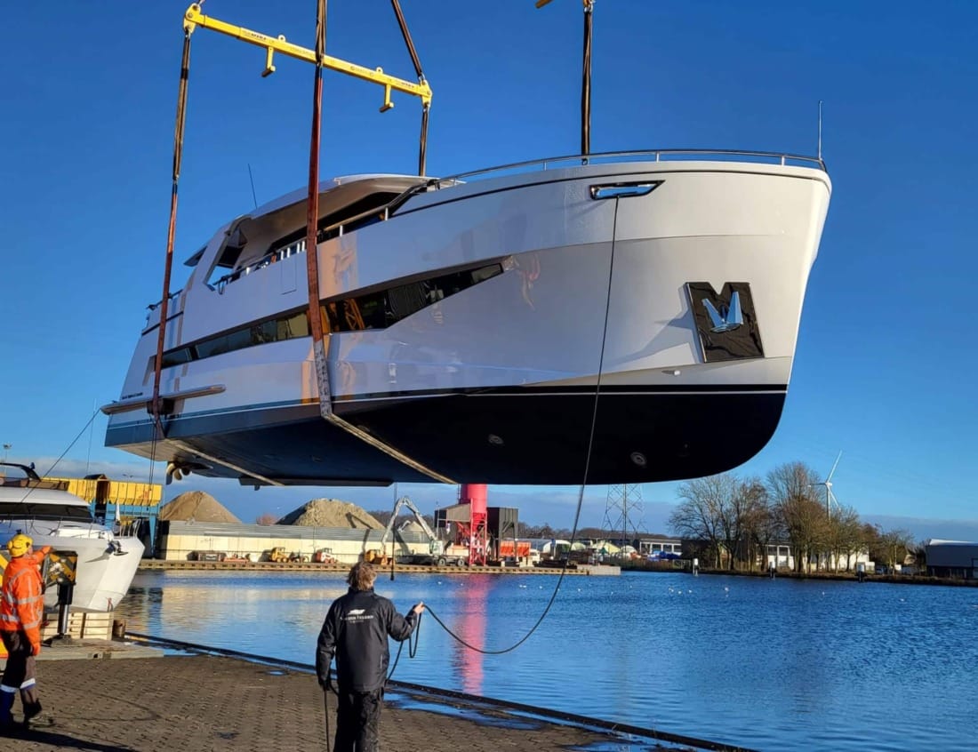 Traveller 63 - Traveller Series being lifted by a crane above a transport trailer at the waterfront.
