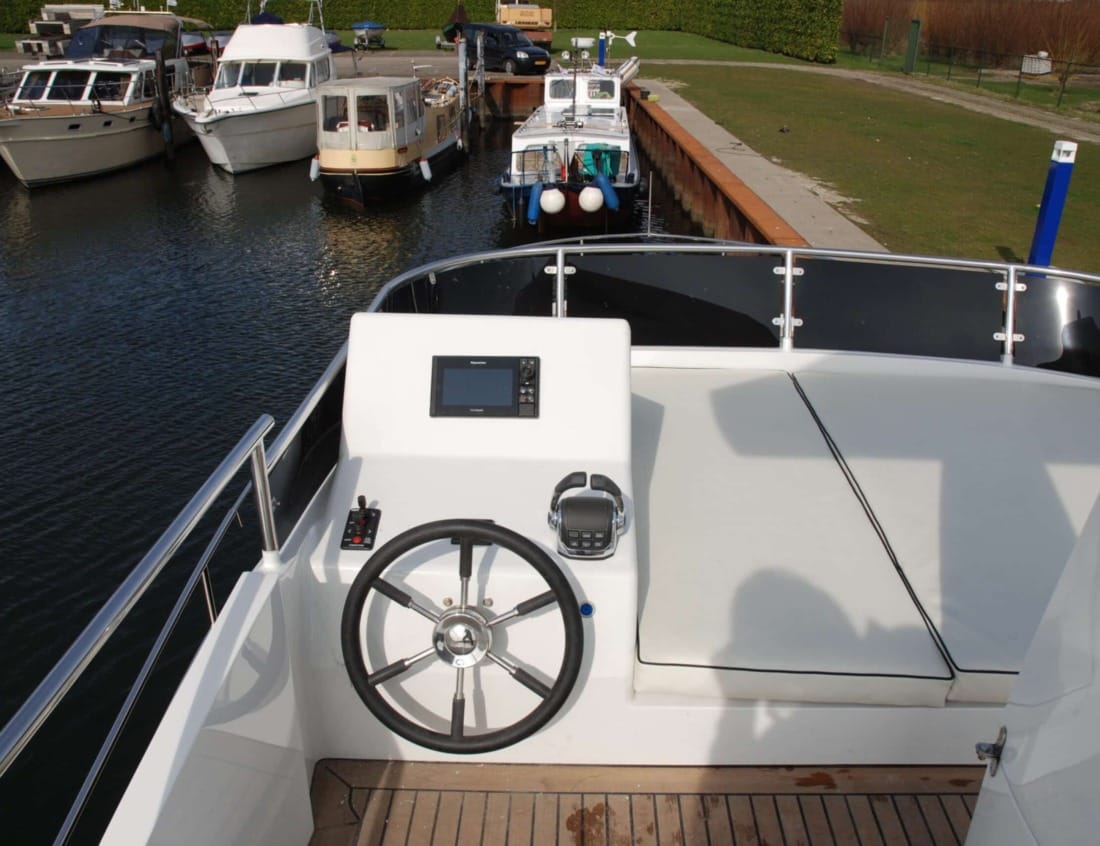 Helm station of a Hayden Flybridge - Hayden Series with steering wheel, navigation display and sunpad seating.